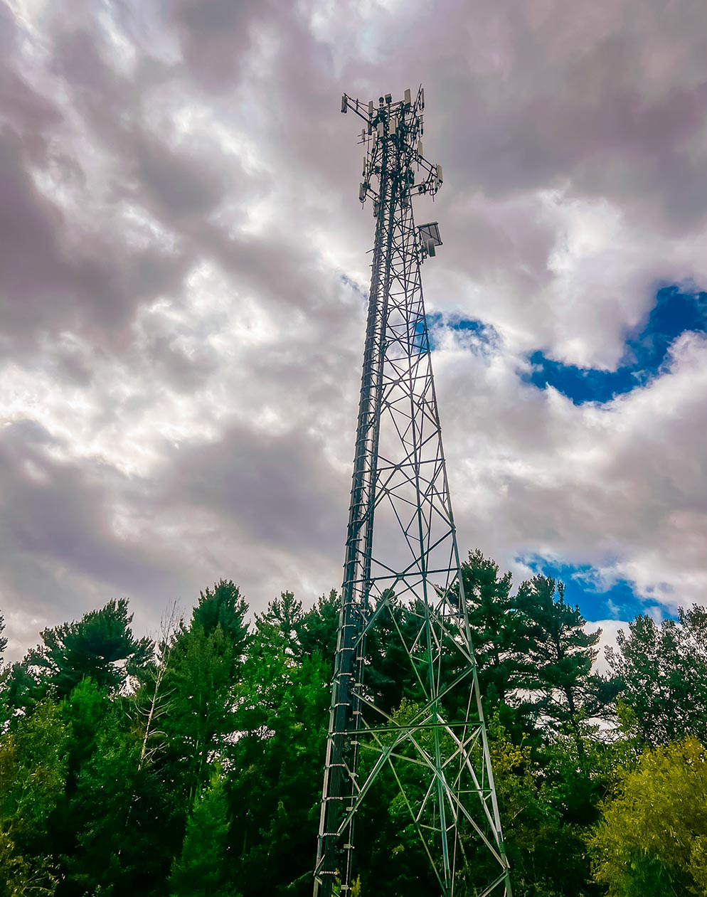 Tour de télécommunication avec antennes cellulaires au-dessus d’une forêt sous un ciel nuageux, infrastructure réseau sans fil en milieu naturel