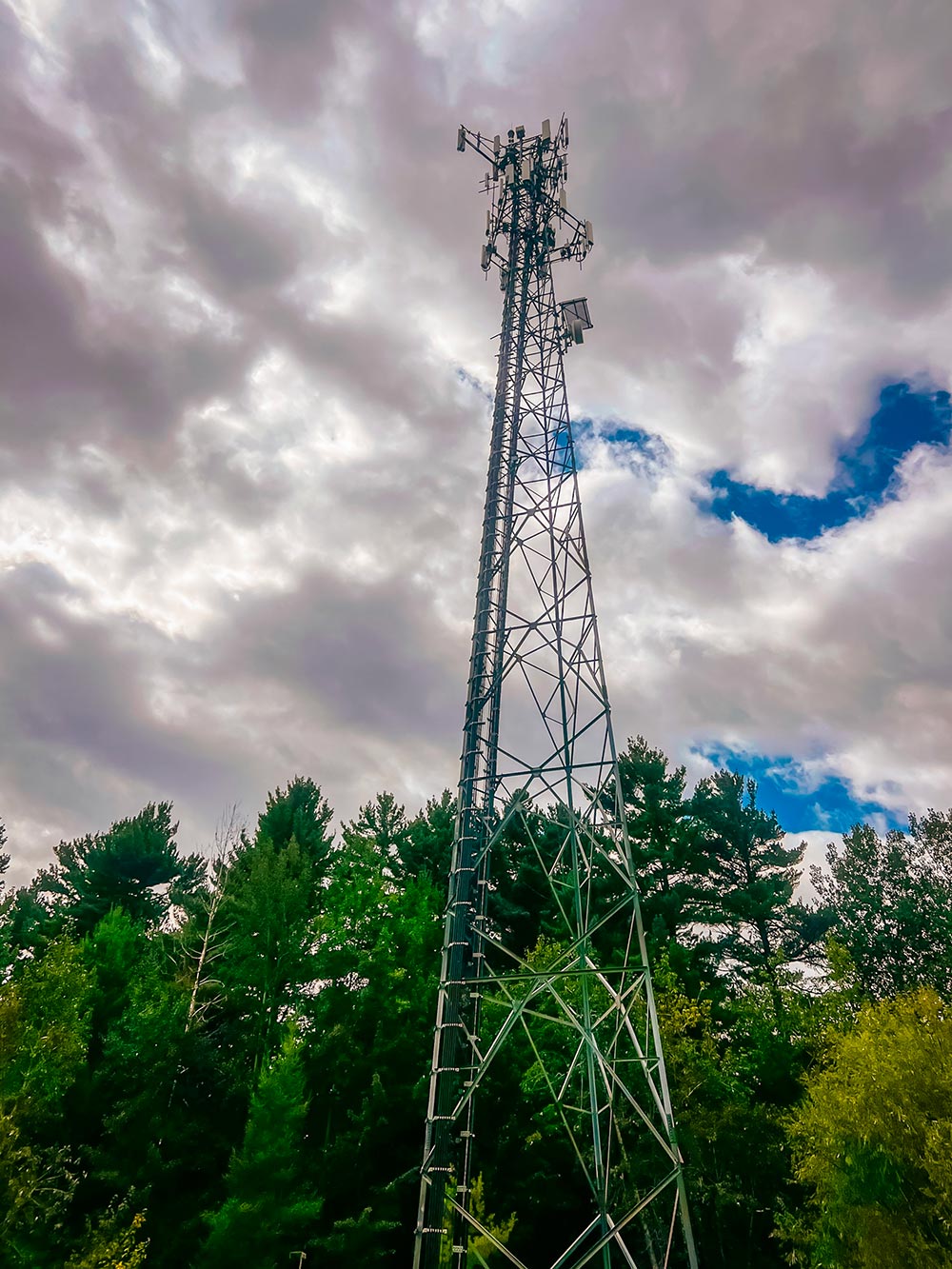 Tour de télécommunication avec antennes de réseau mobile en forêt sous un ciel nuageux au Québec