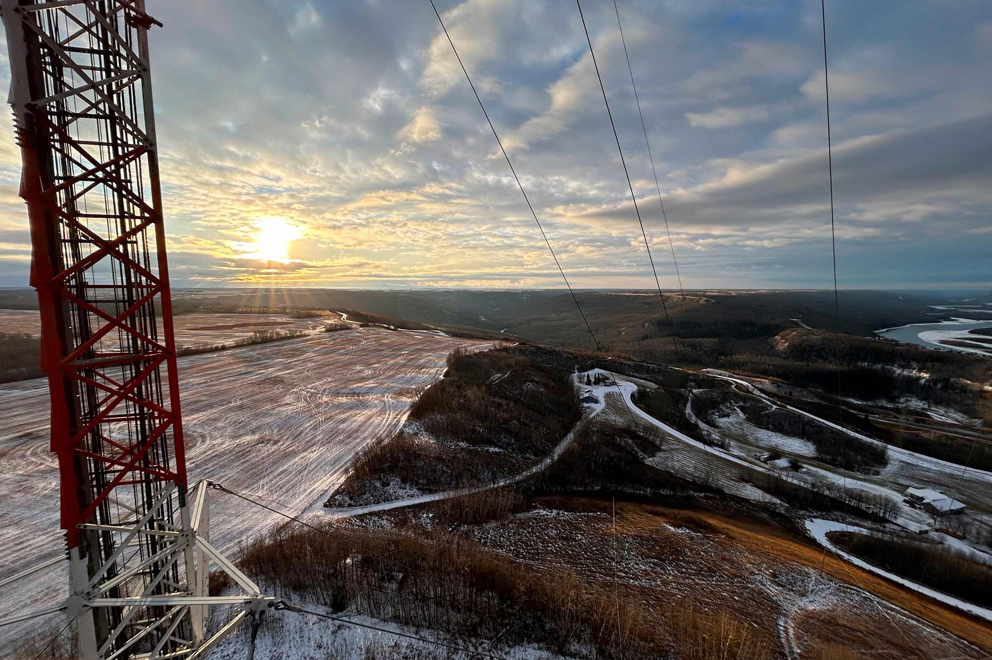 Tour de télécommunication surplombant un paysage de champs enneigés au coucher du soleil au Québec