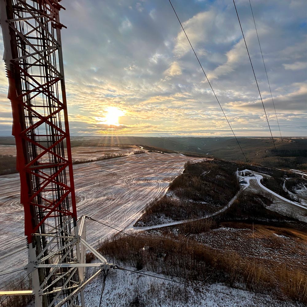 Tour de télécommunication avec câbles surplombant un paysage hivernal au coucher du soleil au Québec