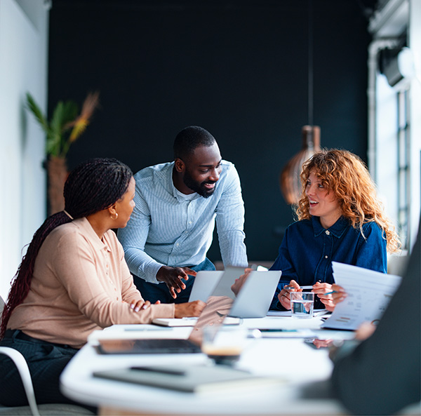 Équipe diversifiée de professionnels collaborant autour d'un ordinateur portable lors d'une réunion de bureau