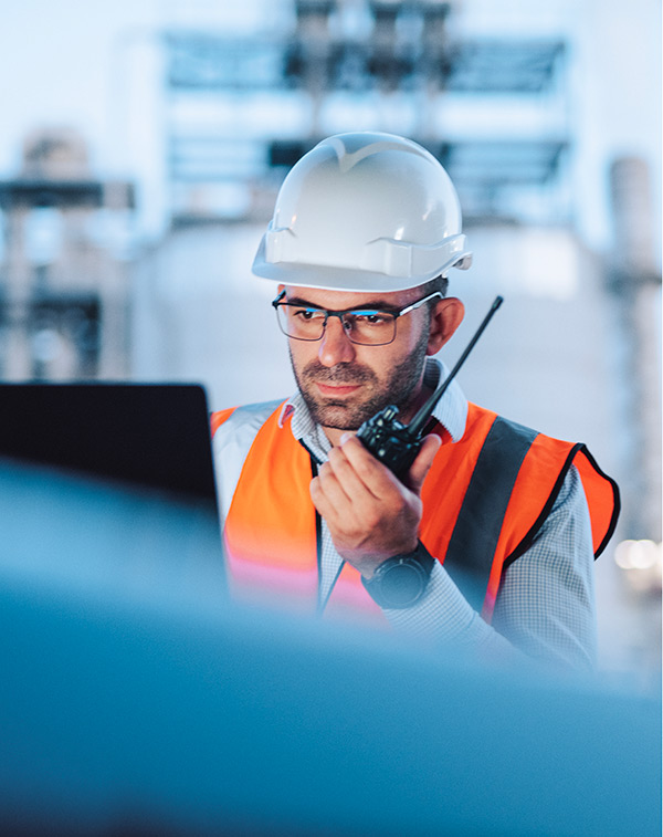 Ingénieur avec casque de sécurité utilisant une radio bidirectionnelle pour coordonner les opérations sur un site industriel