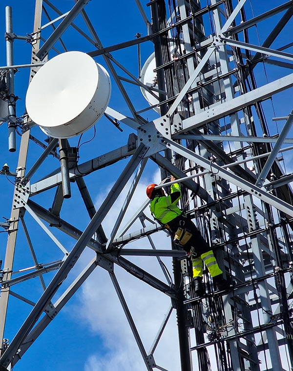 Spécialiste en hauteur procédant à l'installation d'équipements de communication par satellite sur une tour relais