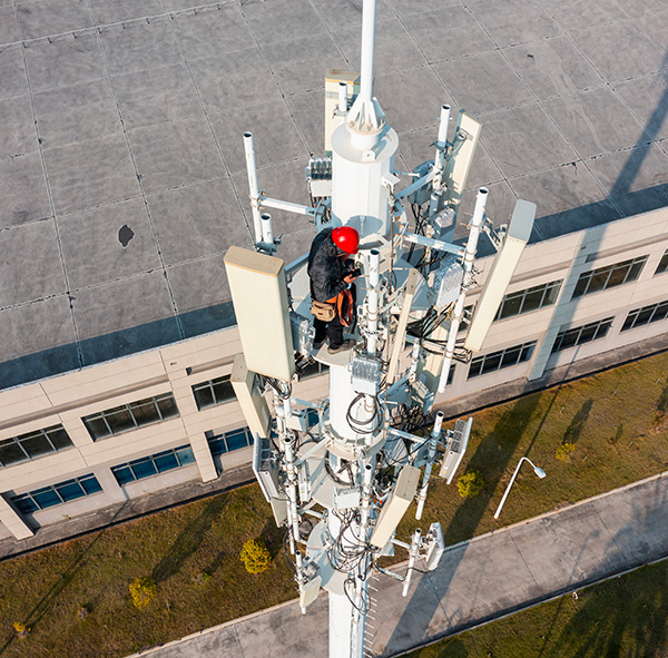 Vue aérienne d'un technicien effectuant la maintenance d'antennes sur une tour cellulaire de télécommunications