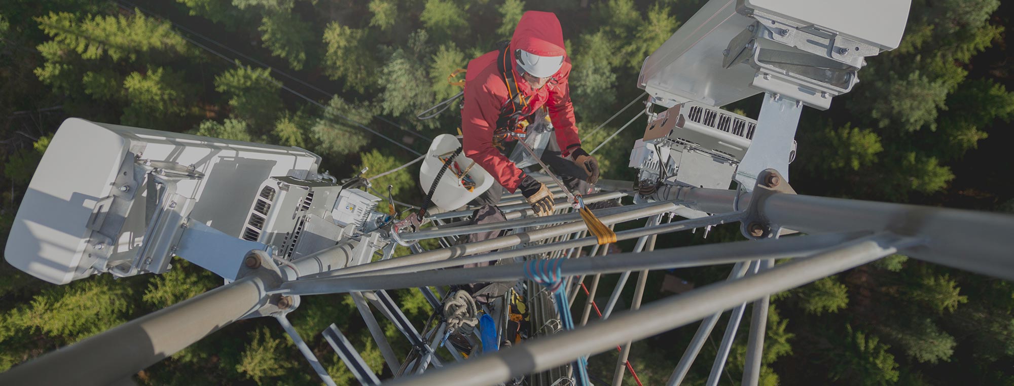 Technicien en télécommunications harnaché effectuant la maintenance d'antennes sur une tour cellulaire en hauteur