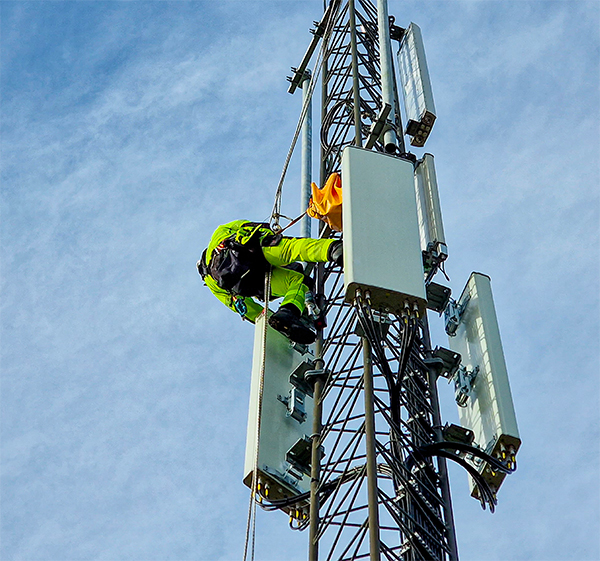 Technicien en télécommunications installant des antennes sur une tour cellulaire en hauteur