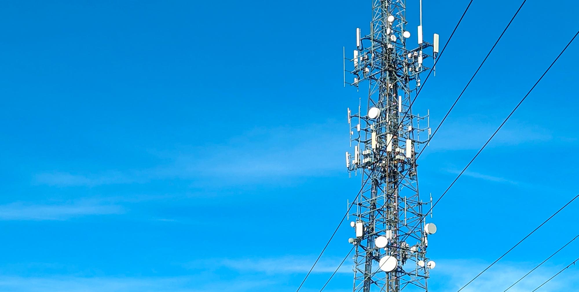 Tour de télécommunication équipée de multiples antennes cellulaires et paraboles sous un ciel bleu