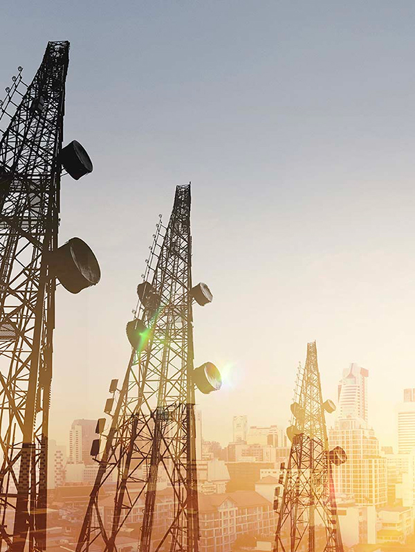 Tours de télécommunications avec antennes-relais surplombant une ville au coucher du soleil
